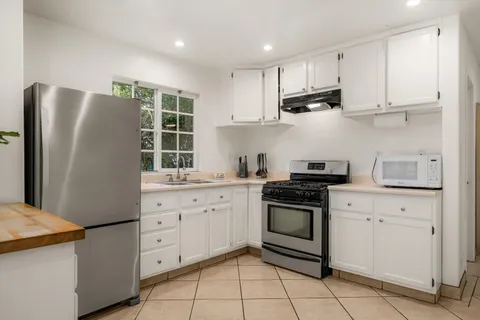 a kitchen with stainless steel appliances granite countertop white cabinets and a refrigerator