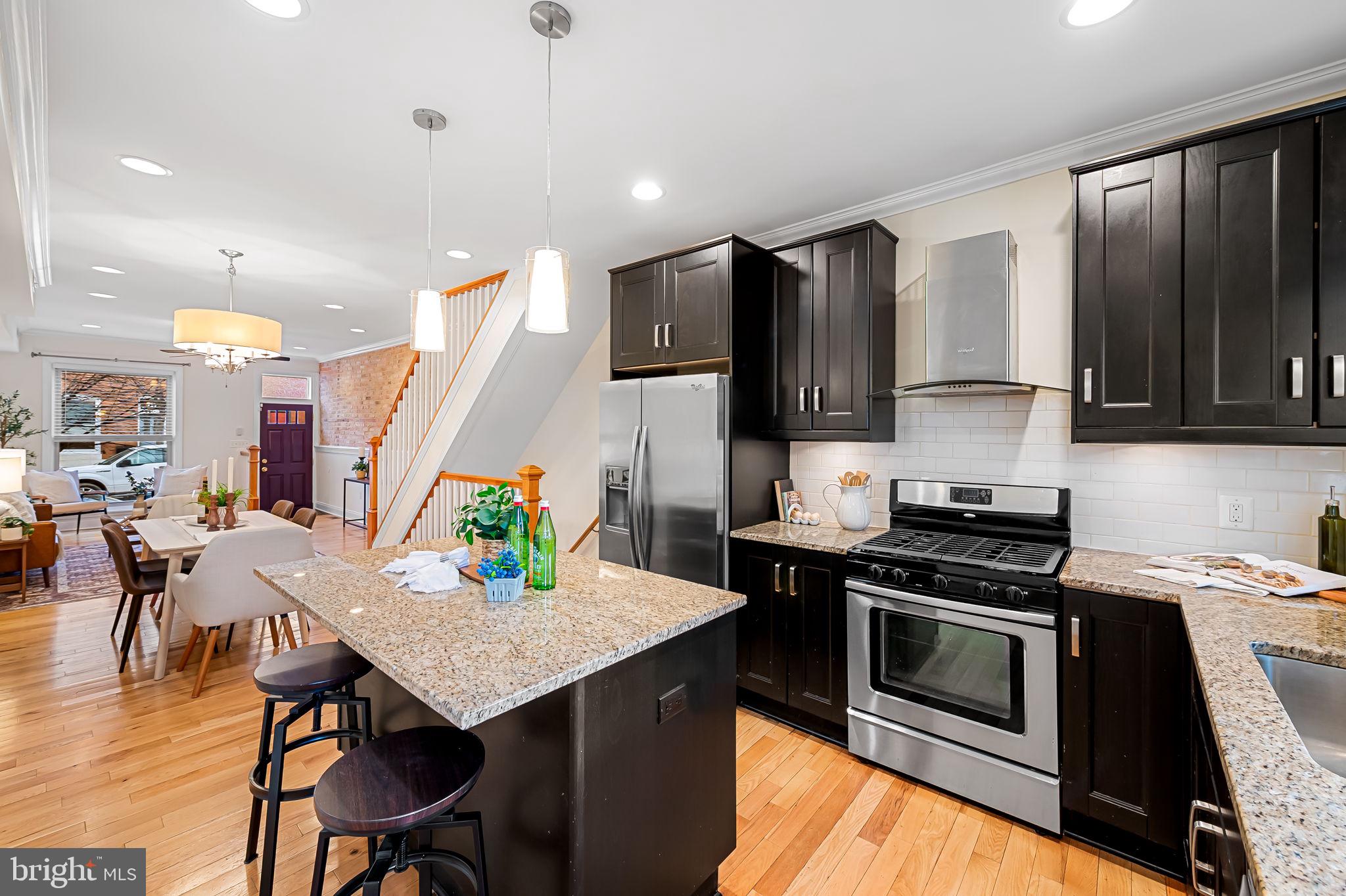 116 Rochester Place Baltimore, MD 21224 - Photo 12 of 45 a kitchen with a stove a microwave a dining table and chairs with wooden floor
