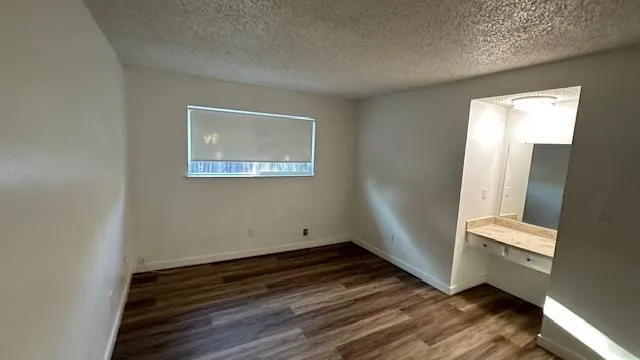 a view of empty room with window and wooden floor