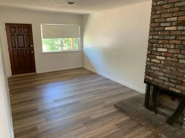 an empty room with wooden floor cabinet and windows
