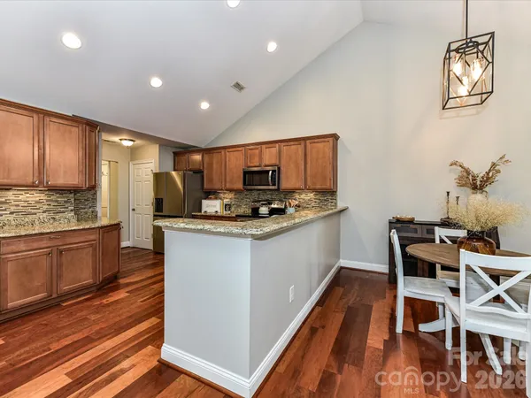 a kitchen with granite countertop kitchen island stainless steel appliances a stove a sink a refrigerator cabinets and dining table