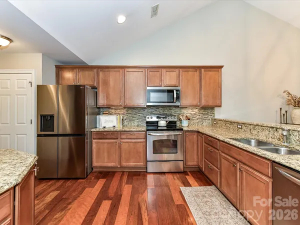a kitchen with granite countertop stainless steel appliances a refrigerator sink and microwave
