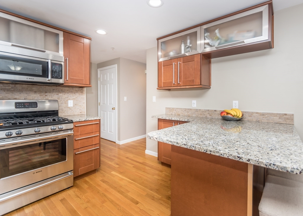 985 Trapelo Road, Unit 23 Waltham, MA 02452 - Photo 9 of 27 a kitchen with stainless steel appliances granite countertop a stove a sink and a microwave