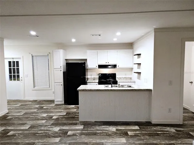 a living room with stainless steel appliances kitchen island granite countertop a table chairs refrigerator and microwave