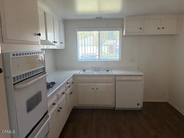 a kitchen with granite countertop white cabinets and white appliances