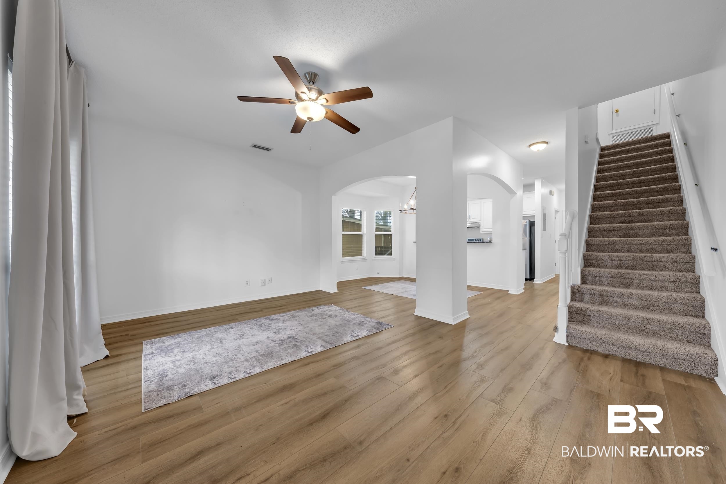 17488 Pandion Ridge, Unit A1 Fairhope, AL 36532 - Photo 5 of 18 Spacious living area featuring wood-finish flooring, white walls, and a ceiling fan with integrated lighting