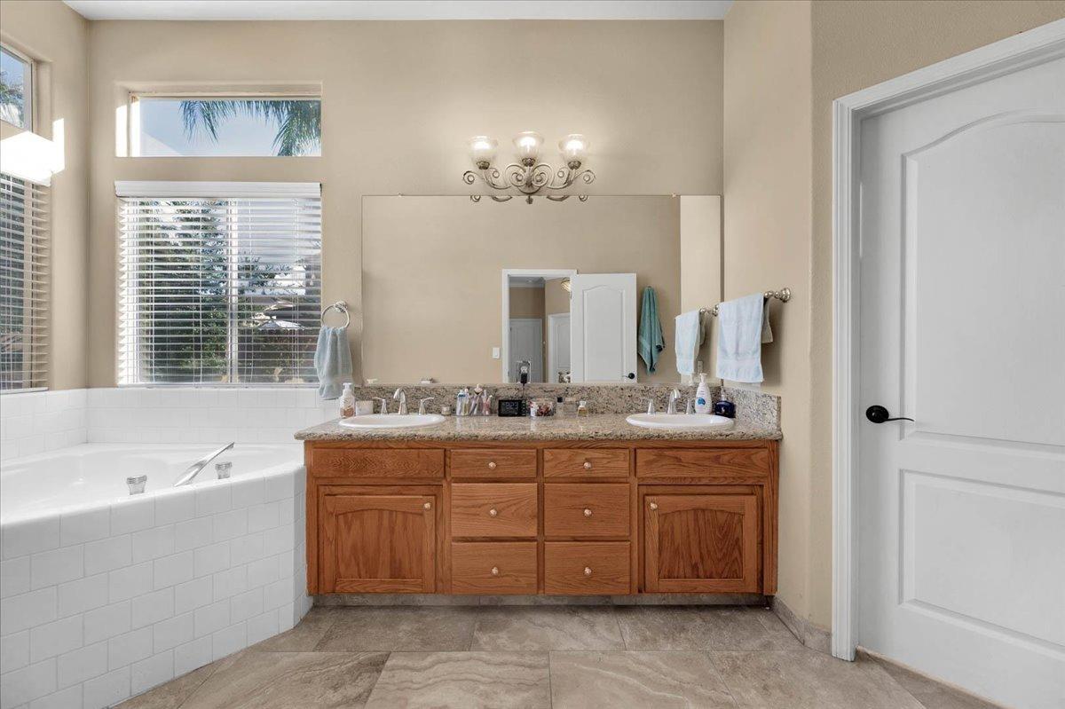 2474 Twain Avenue Clovis, CA 93611 - Photo 28 of 55 a bathroom with a granite countertop double vanity sink large mirror bathtub and window