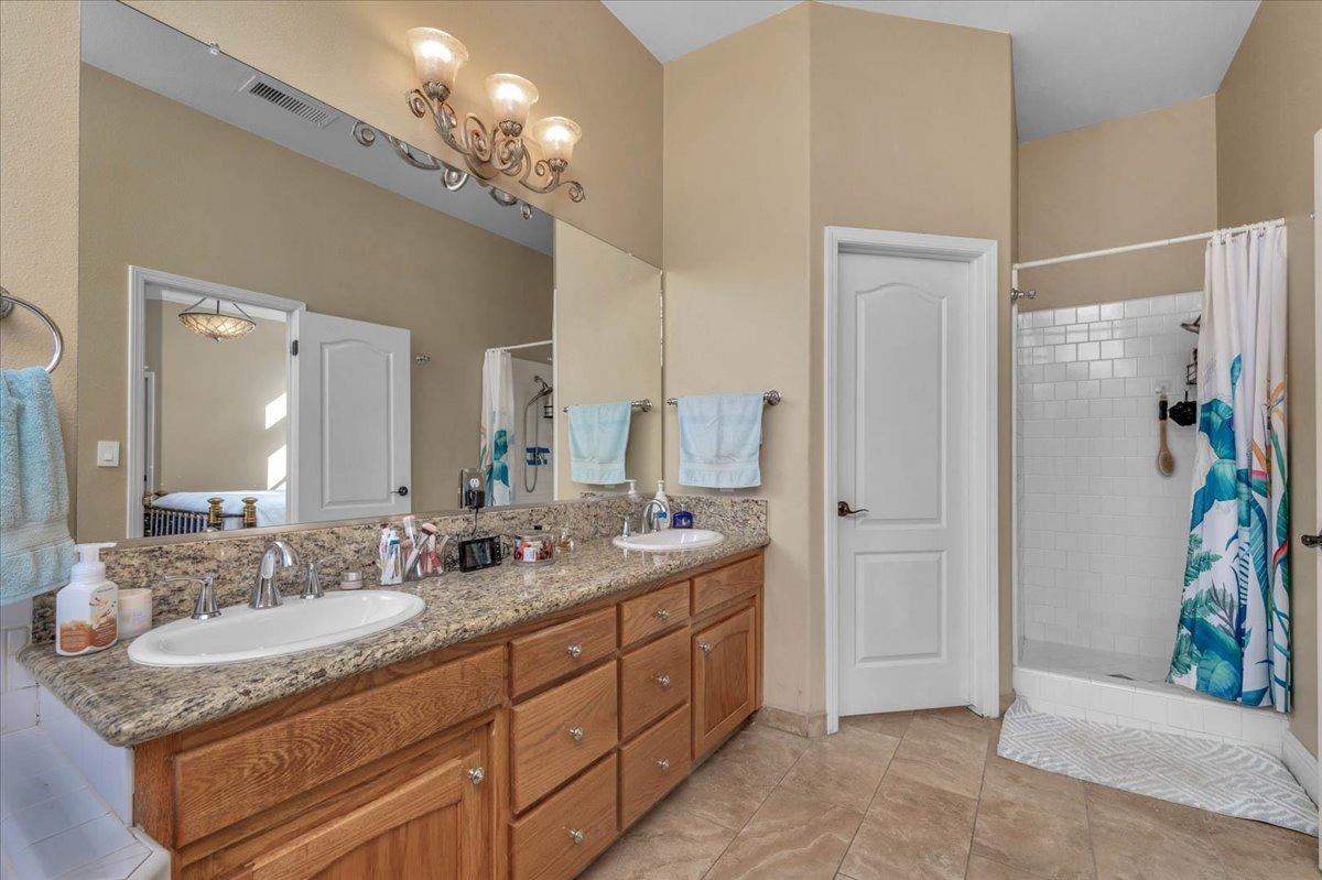 2474 Twain Avenue Clovis, CA 93611 - Photo 30 of 55 a spacious bathroom with a granite countertop sink a mirror and a shower