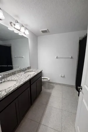 a bathroom with a granite countertop sink a toilet and a mirror