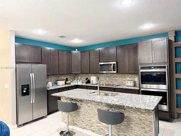 a kitchen with stainless steel appliances granite countertop a refrigerator a stove a sink a counter space and cabinets