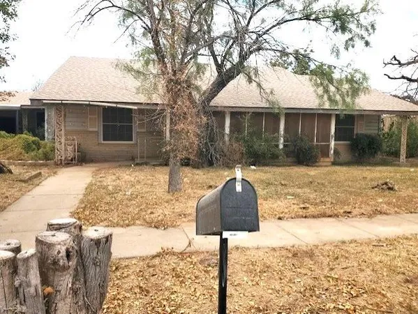 a front view of a house with a yard covered with snow and trees