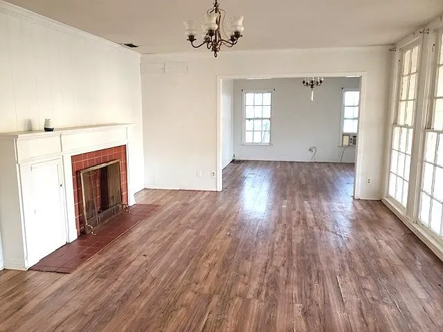 an empty room with wooden floor fireplace and windows