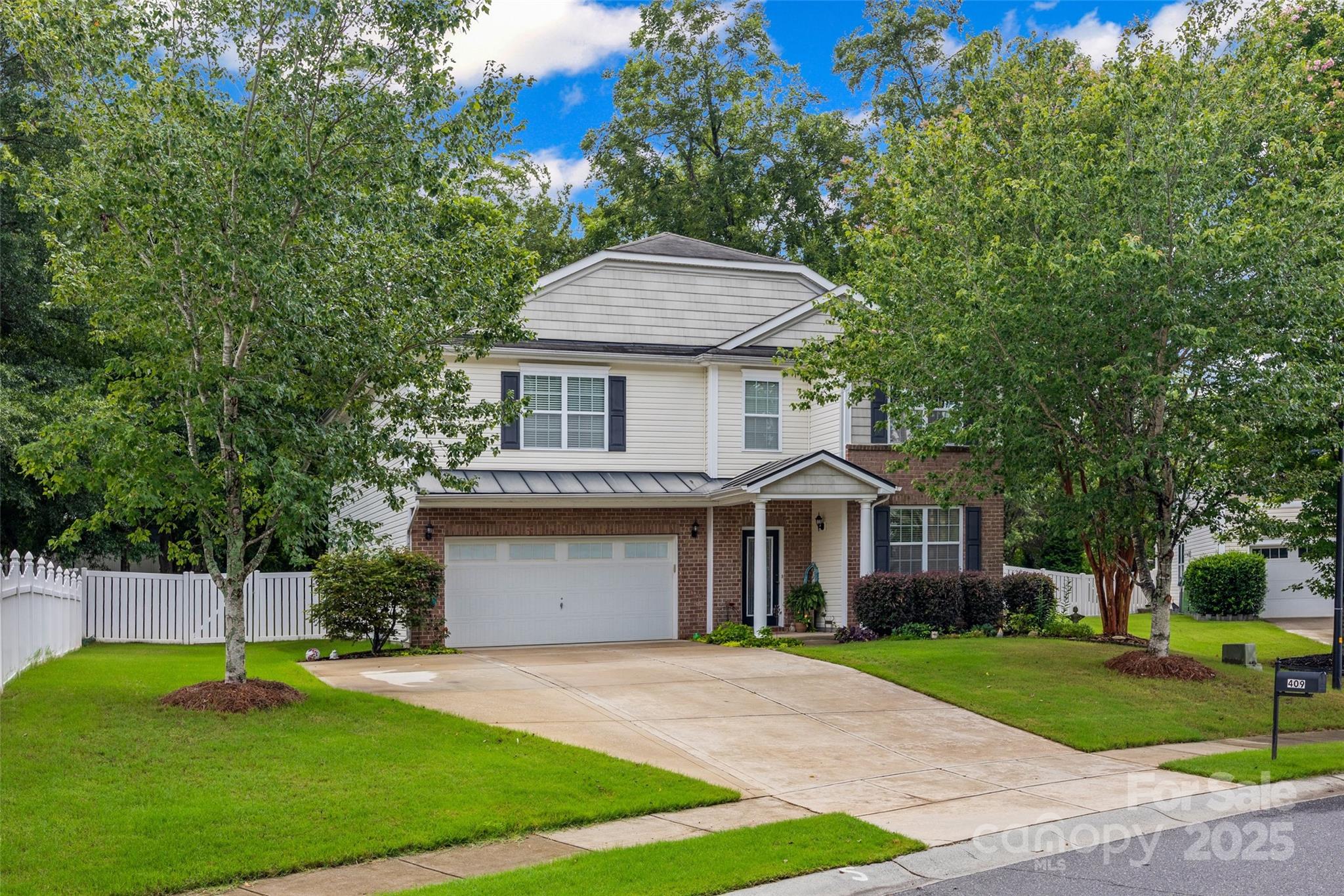 a front view of a house with a garden and trees