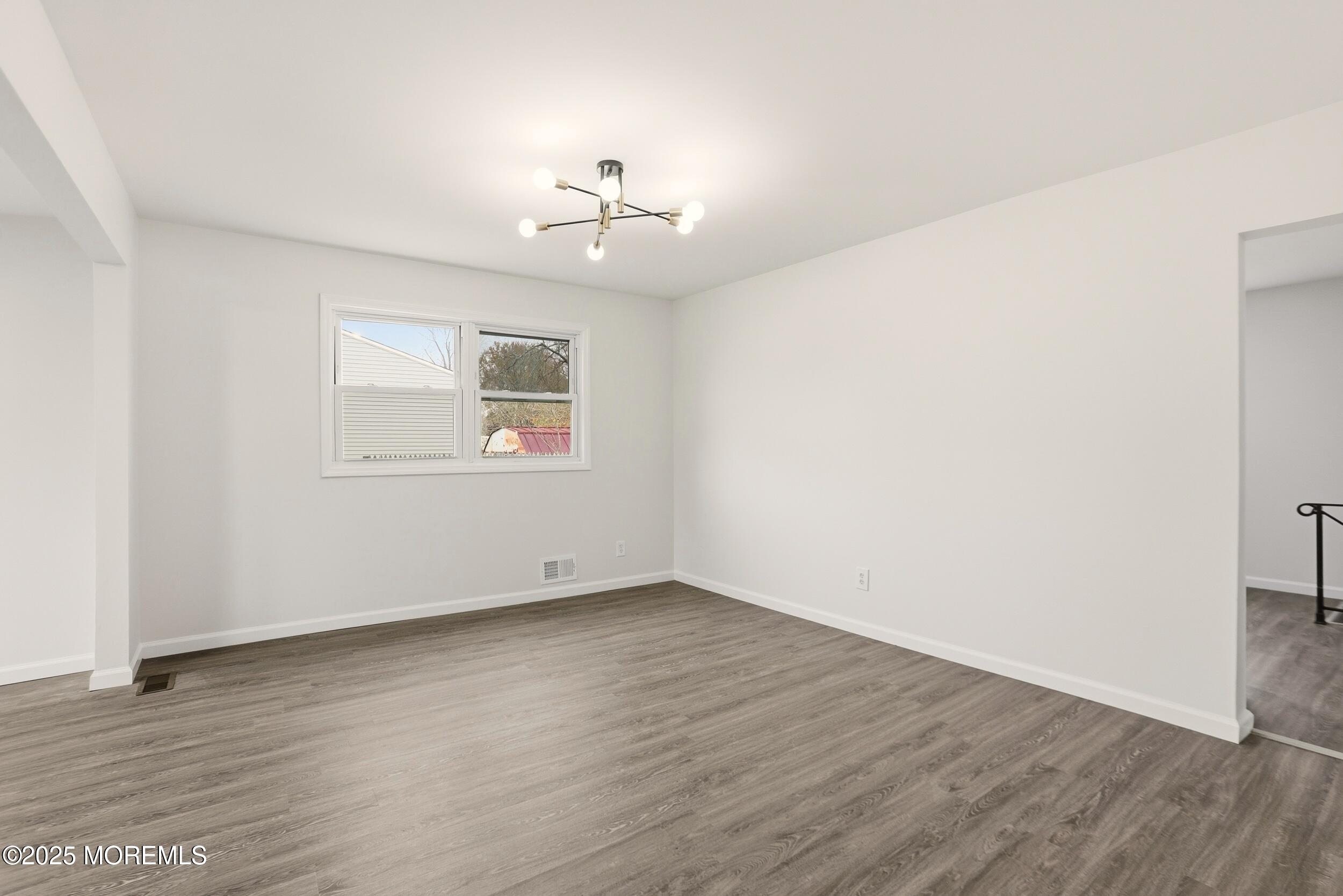 28 Brandies Road Toms River, NJ 08757 - Photo 10 of 30 an empty room with wooden floor chandelier fan and windows