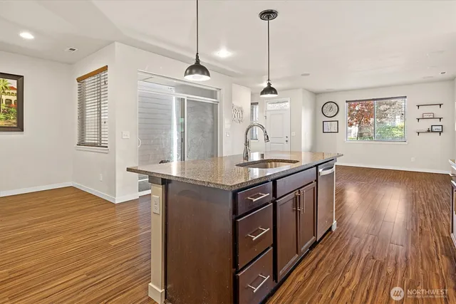 a kitchen with stainless steel appliances granite countertop a sink cabinets and wooden floor