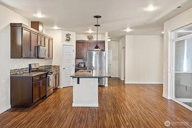 a kitchen with stainless steel appliances wooden floors and wooden cabinets