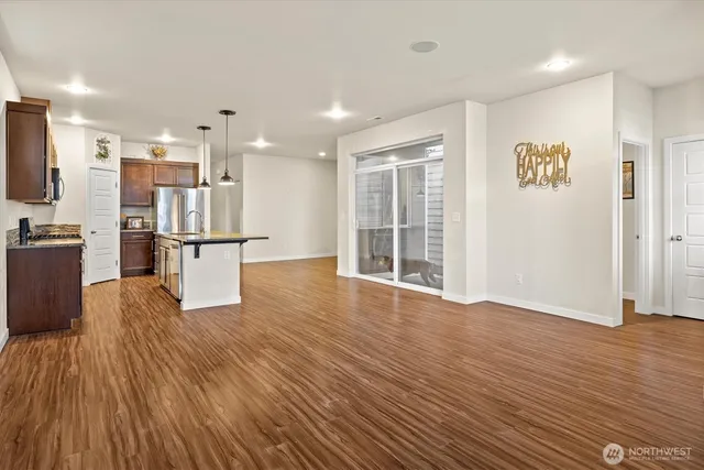 a view of kitchen with stainless steel appliances refrigerator stove and wooden floor