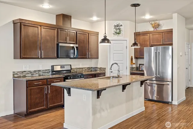 a kitchen with stainless steel appliances granite countertop a refrigerator a stove a sink and a microwave