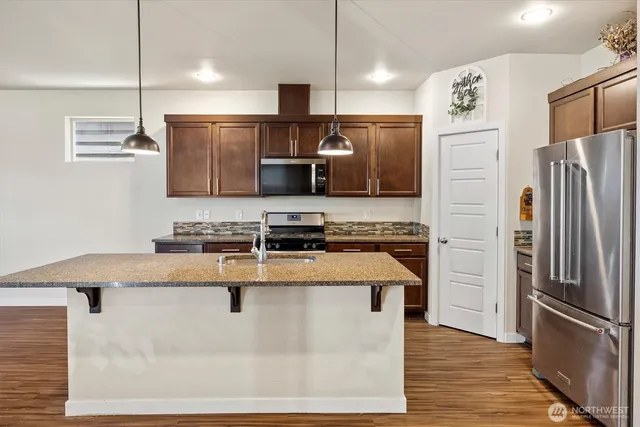 a kitchen with stainless steel appliances granite countertop a refrigerator a stove and a sink