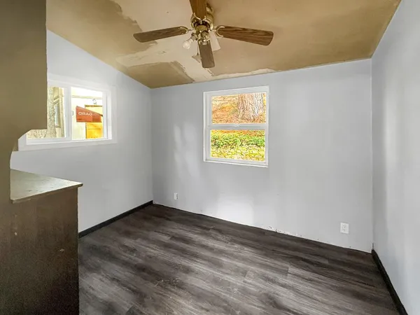 an empty room with windows and fan