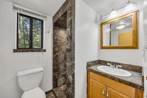 a bathroom with a granite countertop toilet a sink and a mirror
