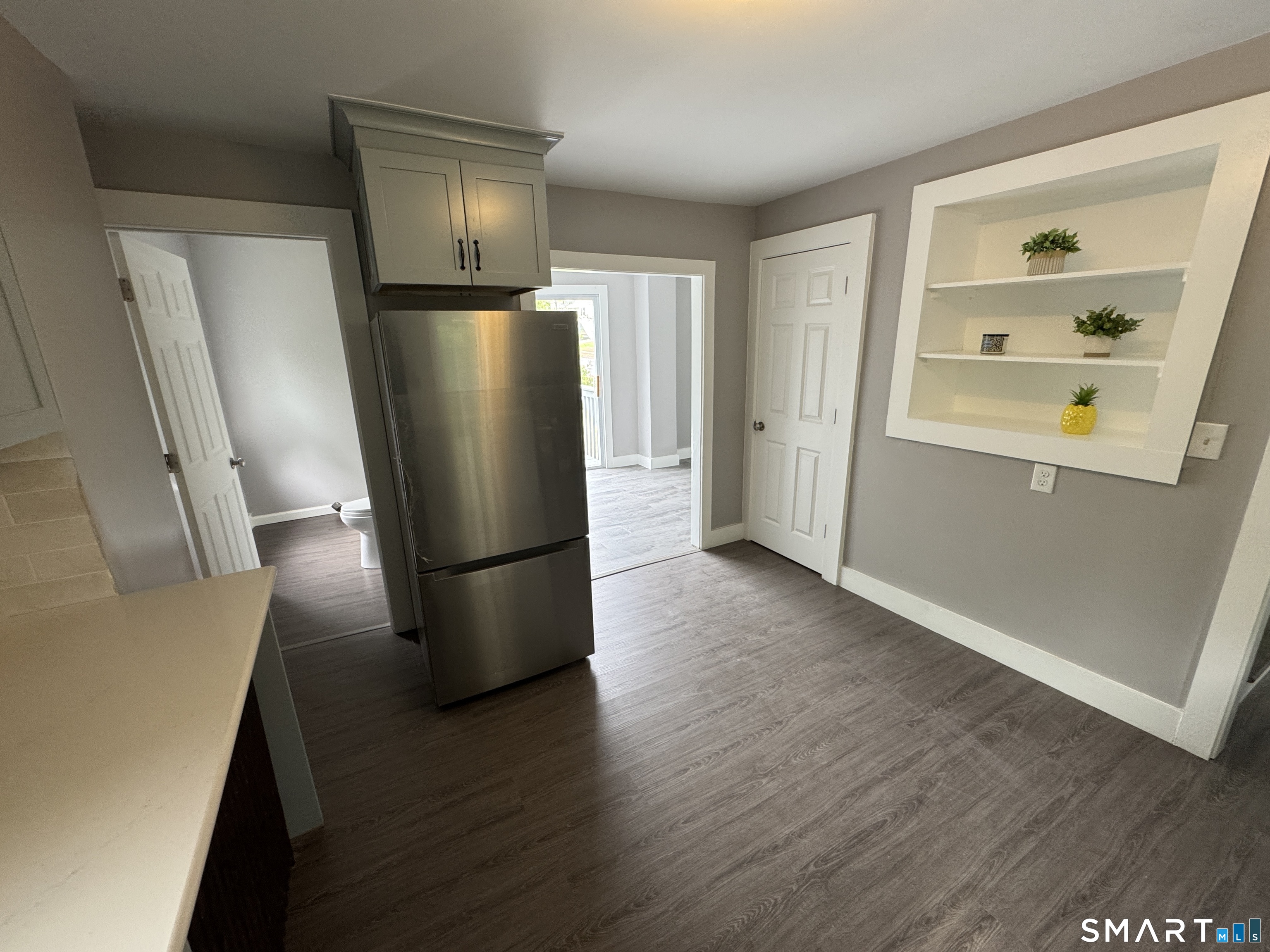 10 Center Street Windsor Locks, CT 06096 - Photo 4 of 25 a view of a refrigerator in kitchen and an empty room with wooden floor