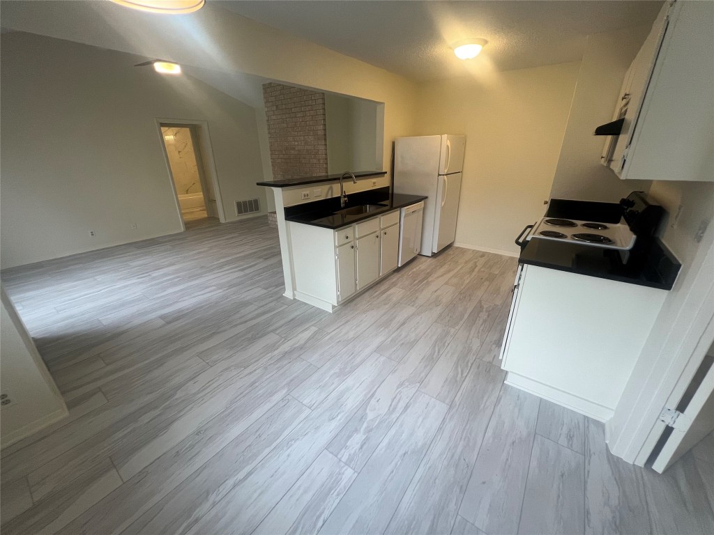 807 Lloyd Lane, Unit A Elgin, TX 78621 - Photo 16 of 16 Kitchen with white cabinets, dark countertops, range with electric cooktop, open floor plan, and lofted ceiling