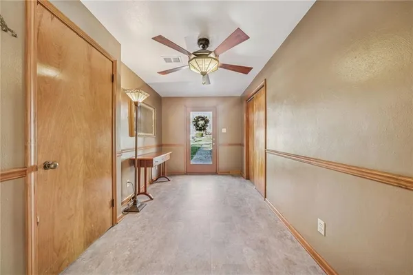a view of a hallway with a chandelier fan and windows