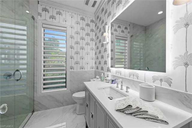 a bathroom with a granite countertop sink a toilet a mirror and shower