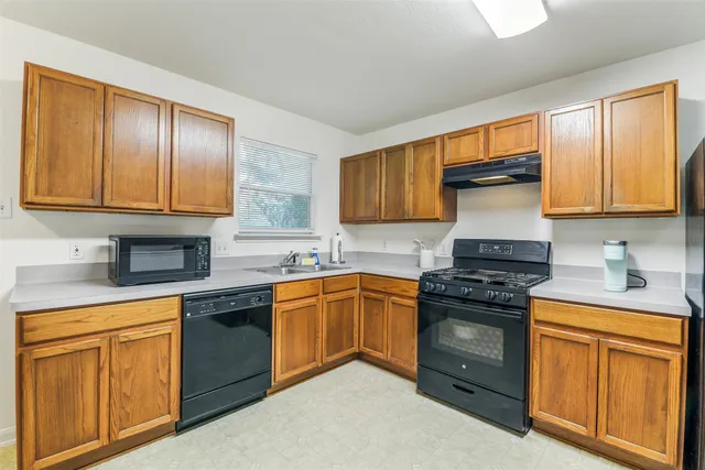 a kitchen with stainless steel appliances granite countertop wooden cabinets stove top oven and sink