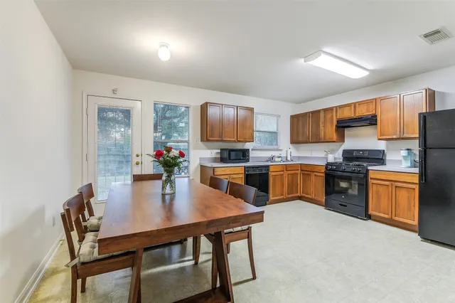 a kitchen with a dining table chairs stainless steel appliances and cabinets