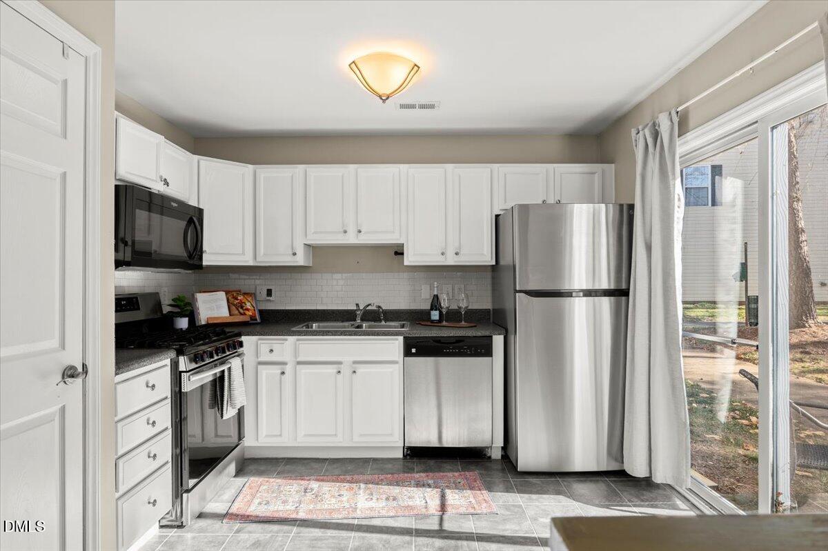2920 Barrymore Street, Unit 106 Raleigh, NC 27603 - Photo 8 of 31 a kitchen with a refrigerator a stove top oven a sink and cabinets