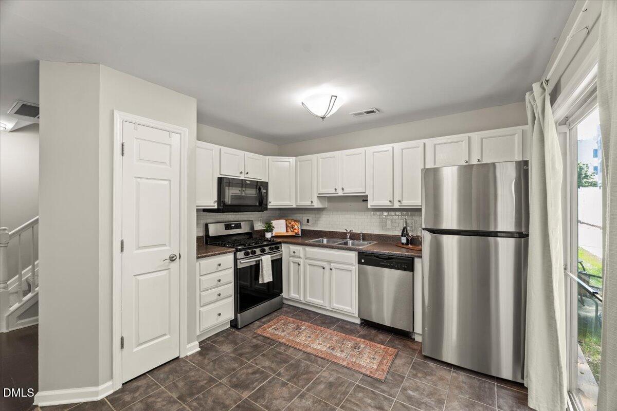 2920 Barrymore Street, Unit 106 Raleigh, NC 27603 - Photo 9 of 31 a kitchen with stainless steel appliances granite countertop a refrigerator stove a sink and dishwasher