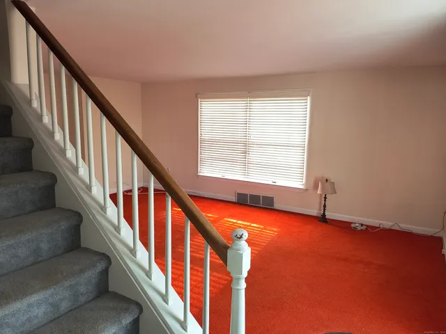 a view of an empty room with wooden floor and stairs