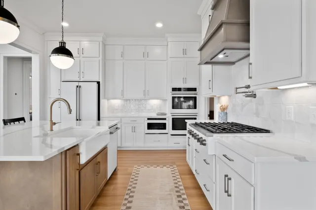 a large kitchen with stainless steel appliances granite countertop a sink a stove and a refrigerator