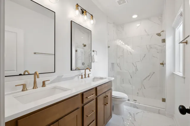 a bathroom with a double vanity sink toilet and shower