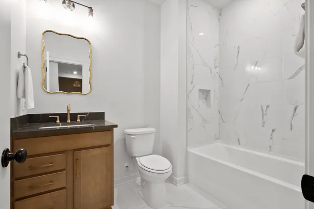 a bathroom with a toilet a sink a mirror a bathtub and vanity