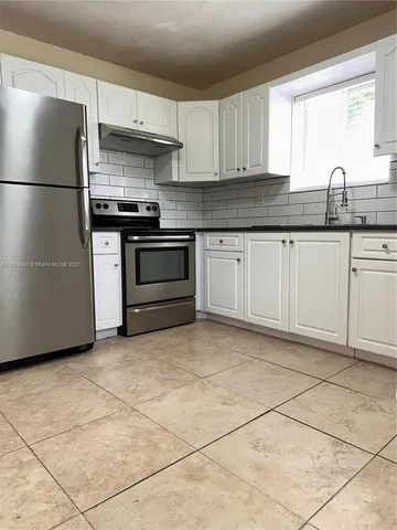 a kitchen with granite countertop a stove a sink and a refrigerator