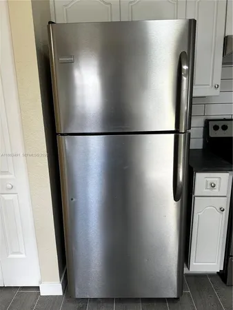 a view of a refrigerator in kitchen and an empty room