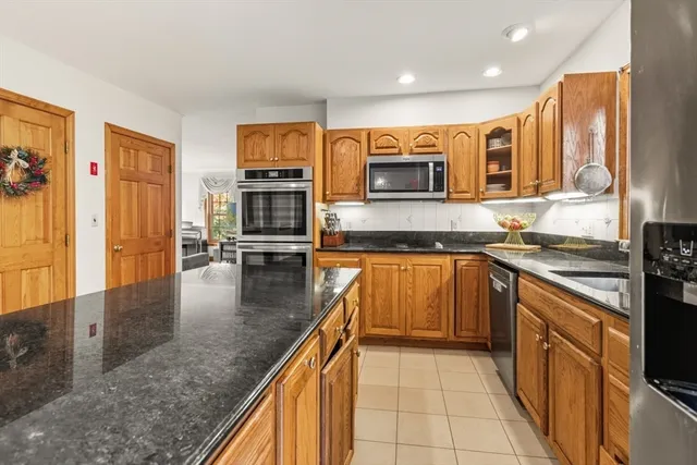 a open kitchen with stainless steel appliances granite countertop a stove top oven a dining table and chairs with wooden floor