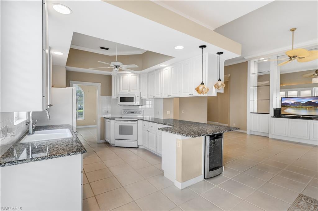 3888 Valentia Way Naples, FL 34119 - Photo 15 of 48 a kitchen with granite countertop a sink stove and refrigerator