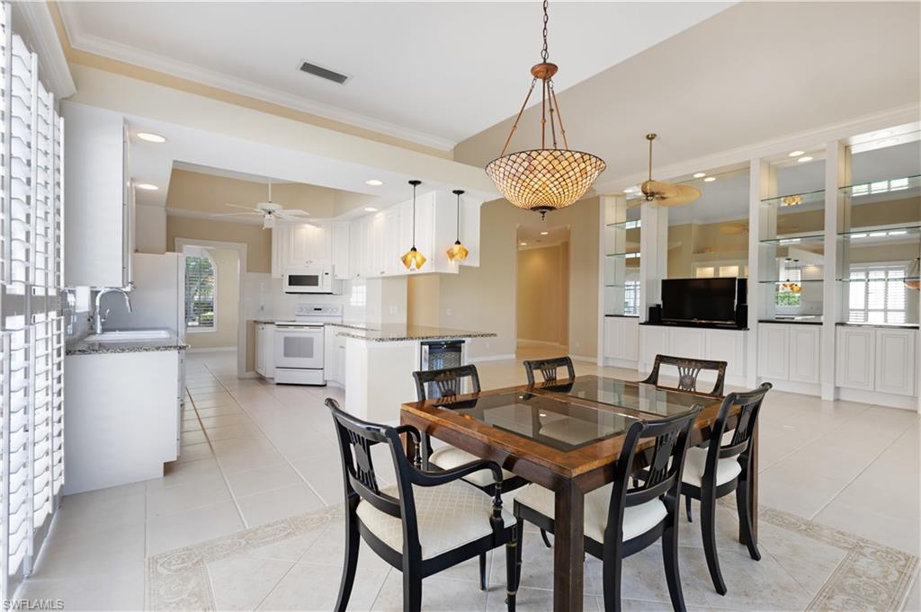 3888 Valentia Way Naples, FL 34119 - Photo 7 of 48 a kitchen with stainless steel appliances kitchen island granite countertop a table chairs and a refrigerator