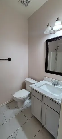 a bathroom with a granite countertop toilet sink and mirror