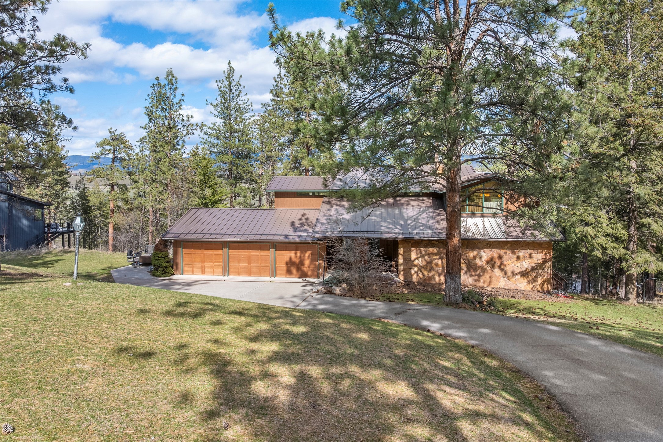 730 Big Flat Road Missoula, MT 59804 - Photo 6 of 59 View of front of house featuring a standing seam roof, driveway, a front lawn, and a garage