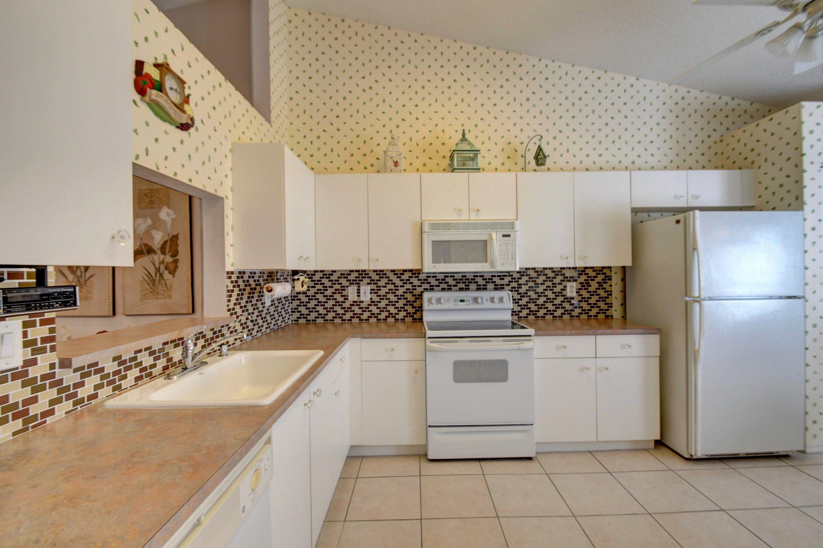 6121 Heliconia Road Delray Beach, FL 33484 - Photo 13 of 49 a kitchen with stainless steel appliances granite countertop a sink stove and refrigerator