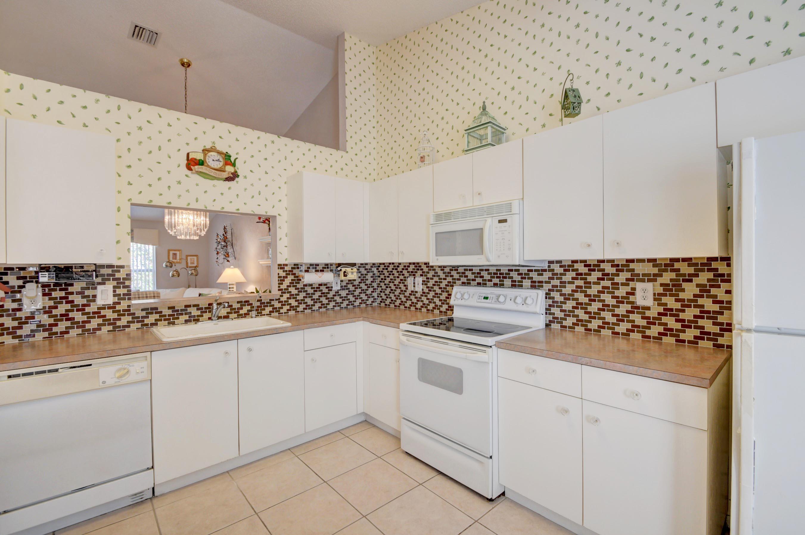 6121 Heliconia Road Delray Beach, FL 33484 - Photo 17 of 49 a kitchen with granite countertop white cabinets and white appliances