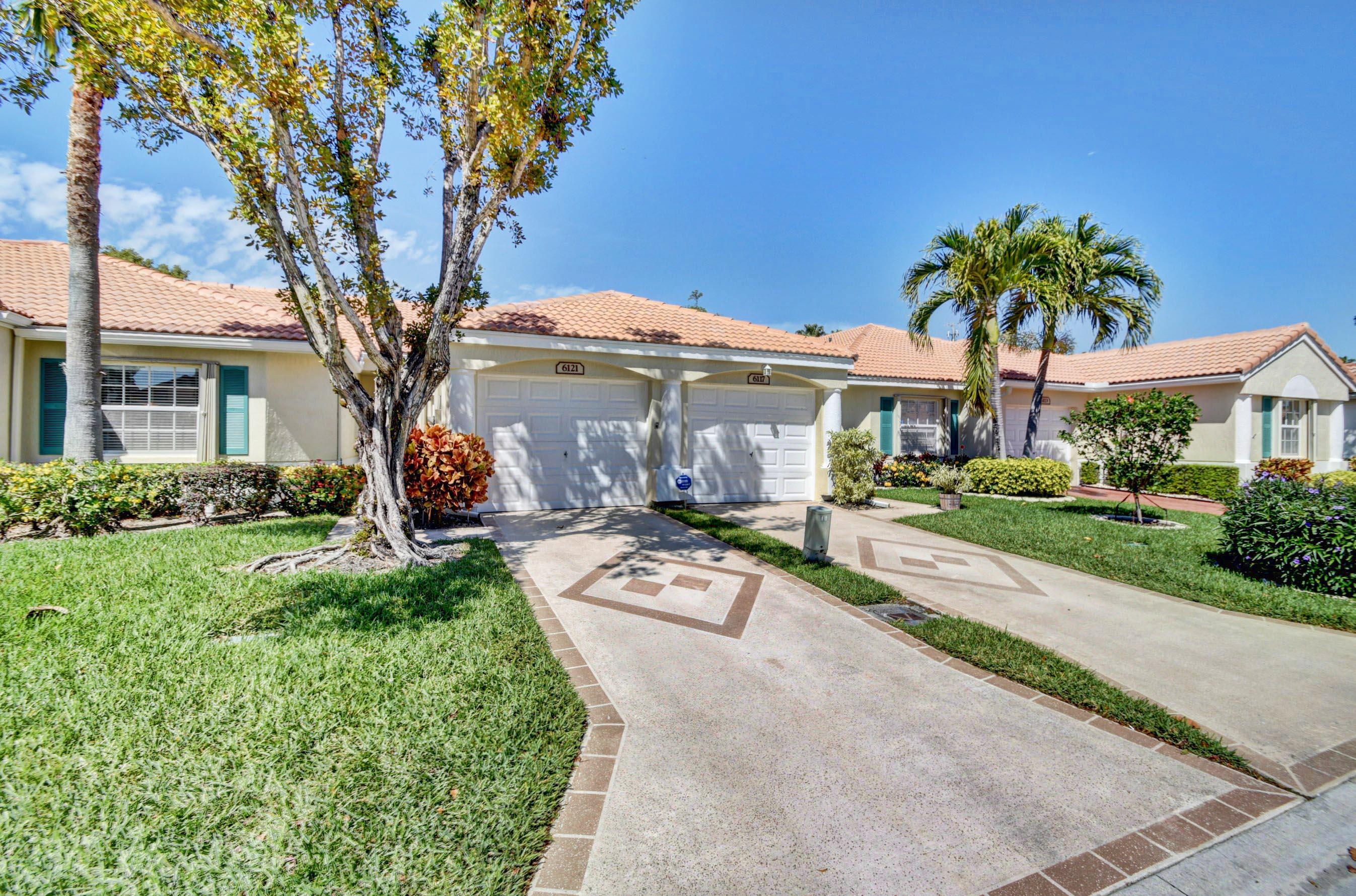 6121 Heliconia Road Delray Beach, FL 33484 - Photo 2 of 49 a view of a white house with a large tree and a yard