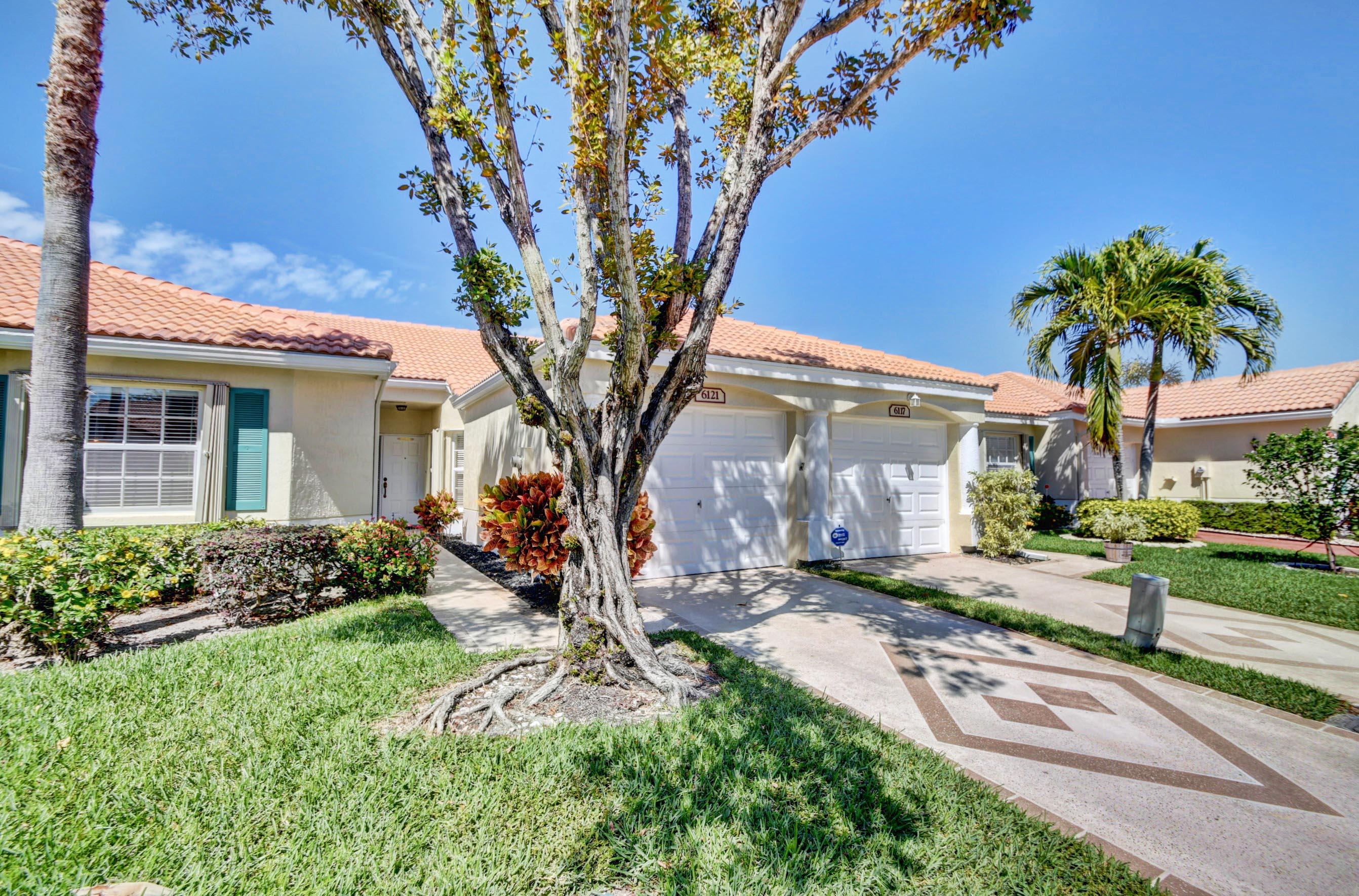 6121 Heliconia Road Delray Beach, FL 33484 - Photo 3 of 49 a front view of a house with garden and trees