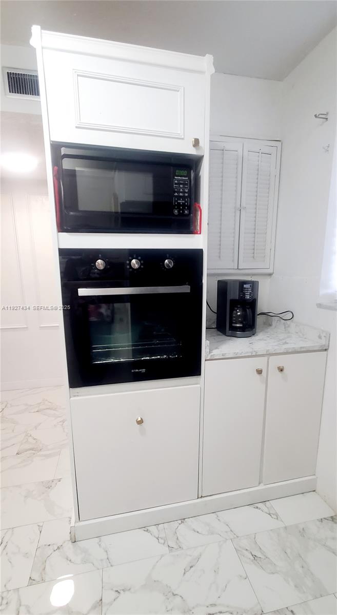 3905 North Nob Hill Road, Unit 510 Sunrise, FL 33351 - Photo 25 of 60 a kitchen with white cabinets and stainless steel appliances