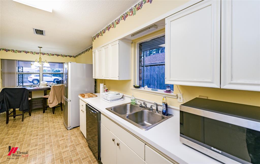 1404 North Acres Circle Springhill, LA 71075 - Photo 13 of 29 Kitchen with stainless steel microwave, white cabinetry, light countertops, a chandelier, and black dishwasher